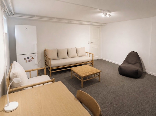 A room with a sofa, a chair, a table, a lamp, a small stool, and a dark bean bag. - Spacious & Cozy Apartment in Copenhagen (København)