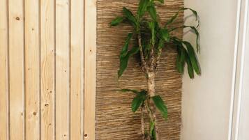 A room with a wooden panel wall, a woven wall panel, and a potted plant in a basket.