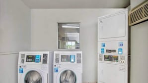 A laundry room with two front-loading washing machines and a stacked dryer. - Cozy 1 Queen Bed | Mini Fridge (Austin TX)