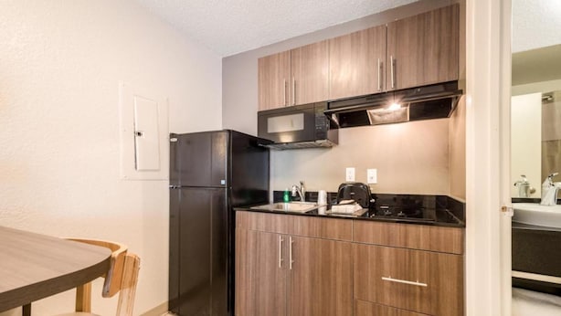 Una cocina funcional con refrigerador, microondas, estufa y gabinetes de madera.