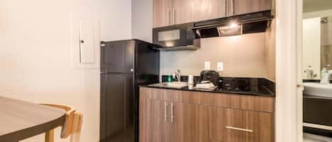 A compact kitchen with a refrigerator, microwave, stove, and wooden cabinets.