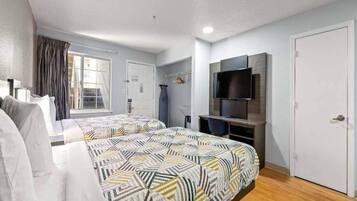 Habitación de hotel con dos camas, un televisor y una ventana con cortinas.