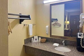 Baño con encimera de granito, lavamanos, toallero, espejo y secador de pelo.