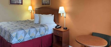 Ein Hotelzimmer mit einem Bett, Nachttischlampen, einem Nachttisch, einem Sessel und zwei Wandbildern.