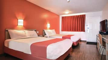 A hotel room with two beds, a desk, and a television.