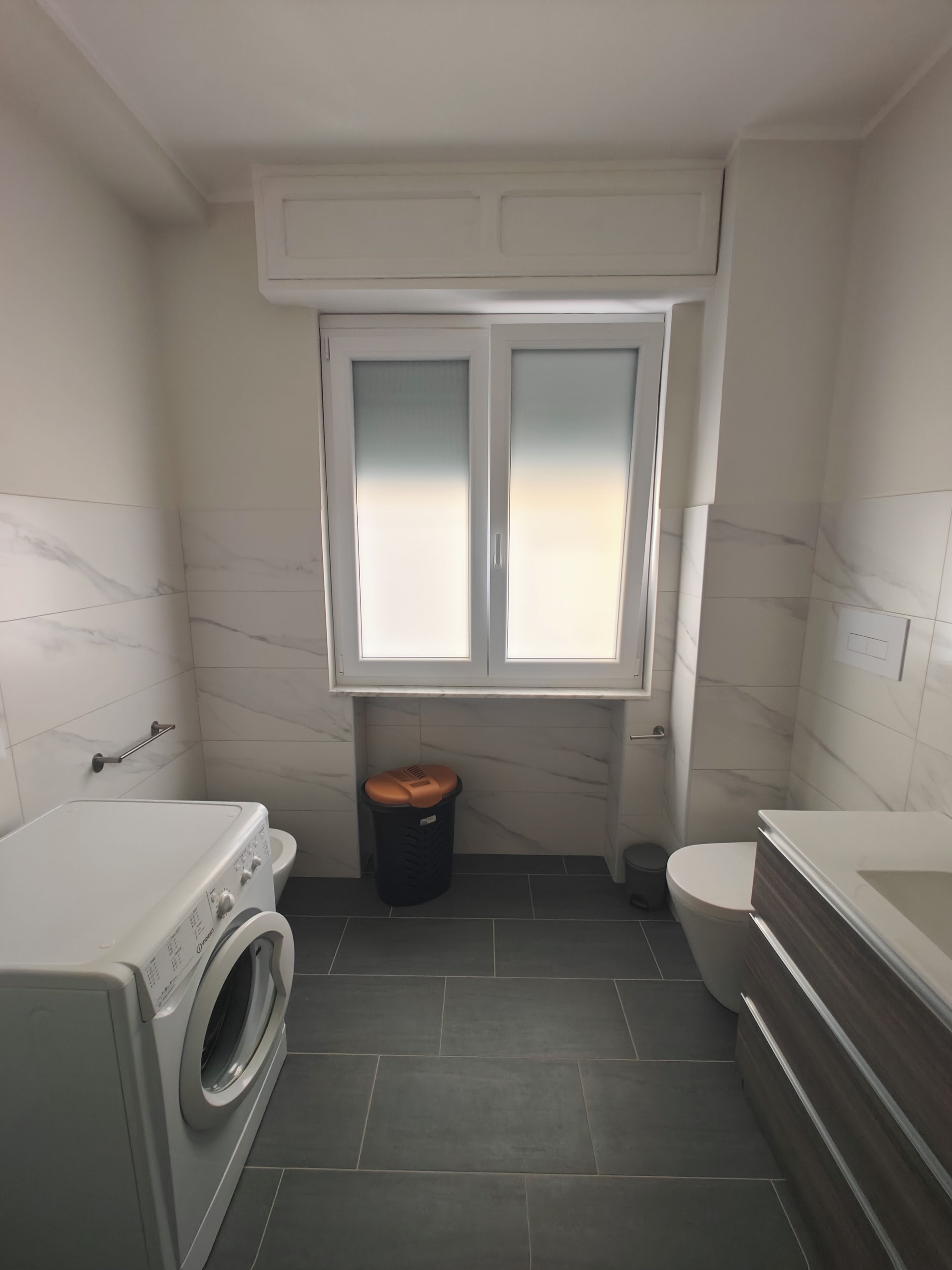 Une petite salle de bain équipée d’un lave-linge, de toilettes et d’une baignoire.