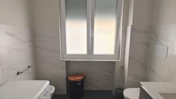 Ein kleines Badezimmer mit Waschmaschine, Toilette und Badewanne.