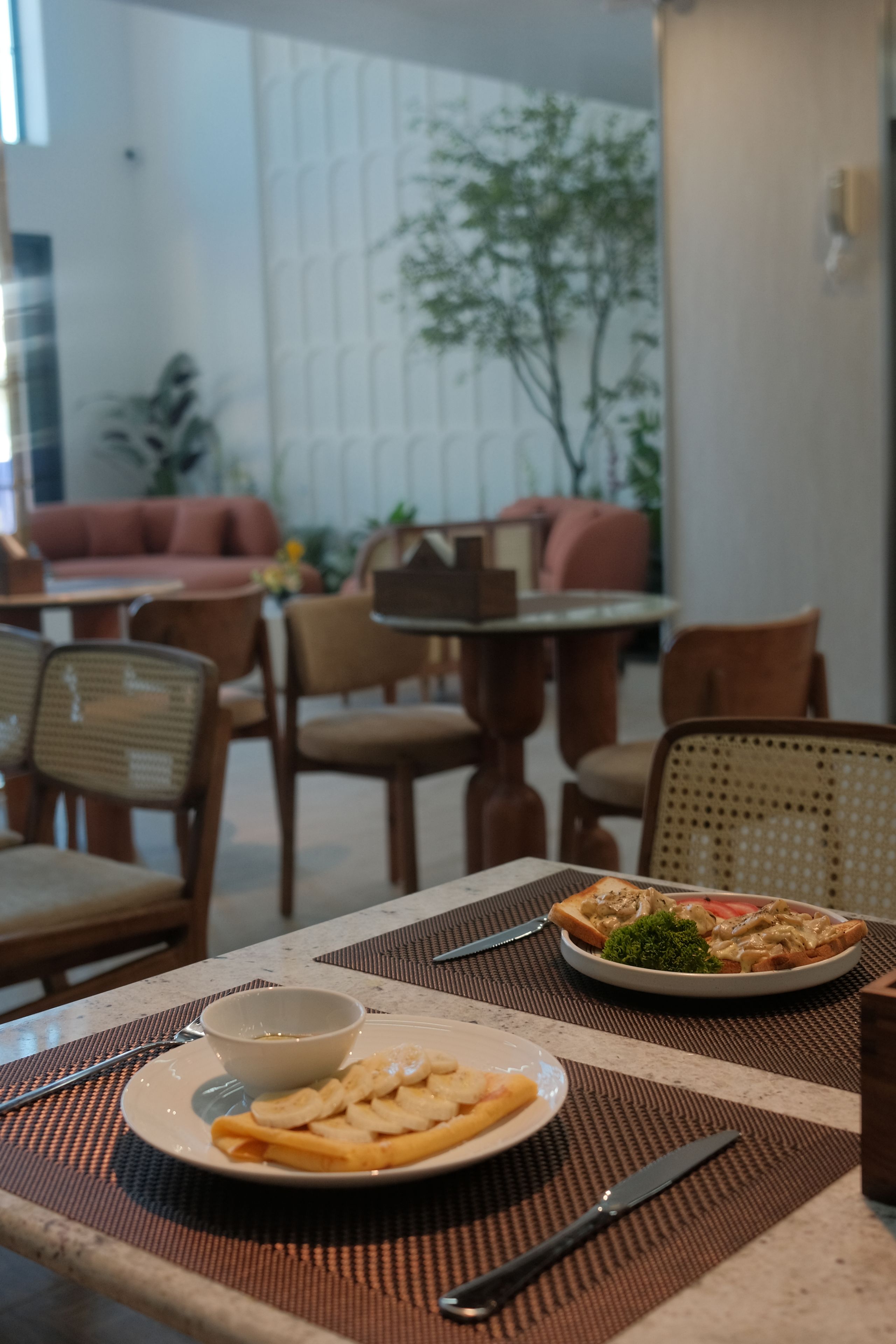 A dining table with a plate of food, a bowl, and cutlery.
