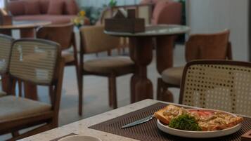 A dining table with a plate of food, a bowl, and cutlery.