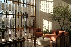 Un interior moderno con una zona de estar, un separador de vidrio decorativo y vistas al exterior.