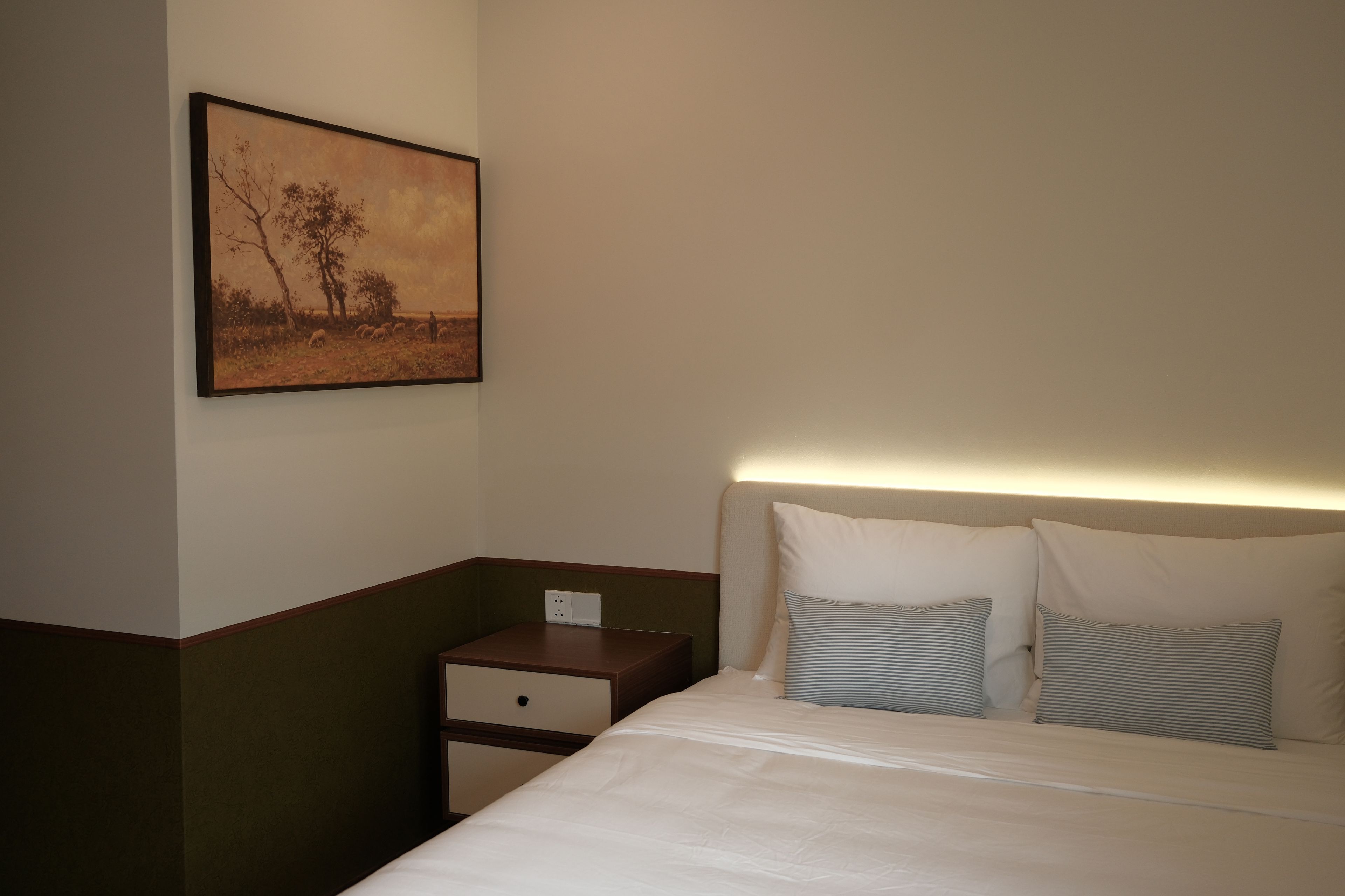 Ein Hotelzimmer mit Bett, Nachttisch und einem Bild an der Wand.