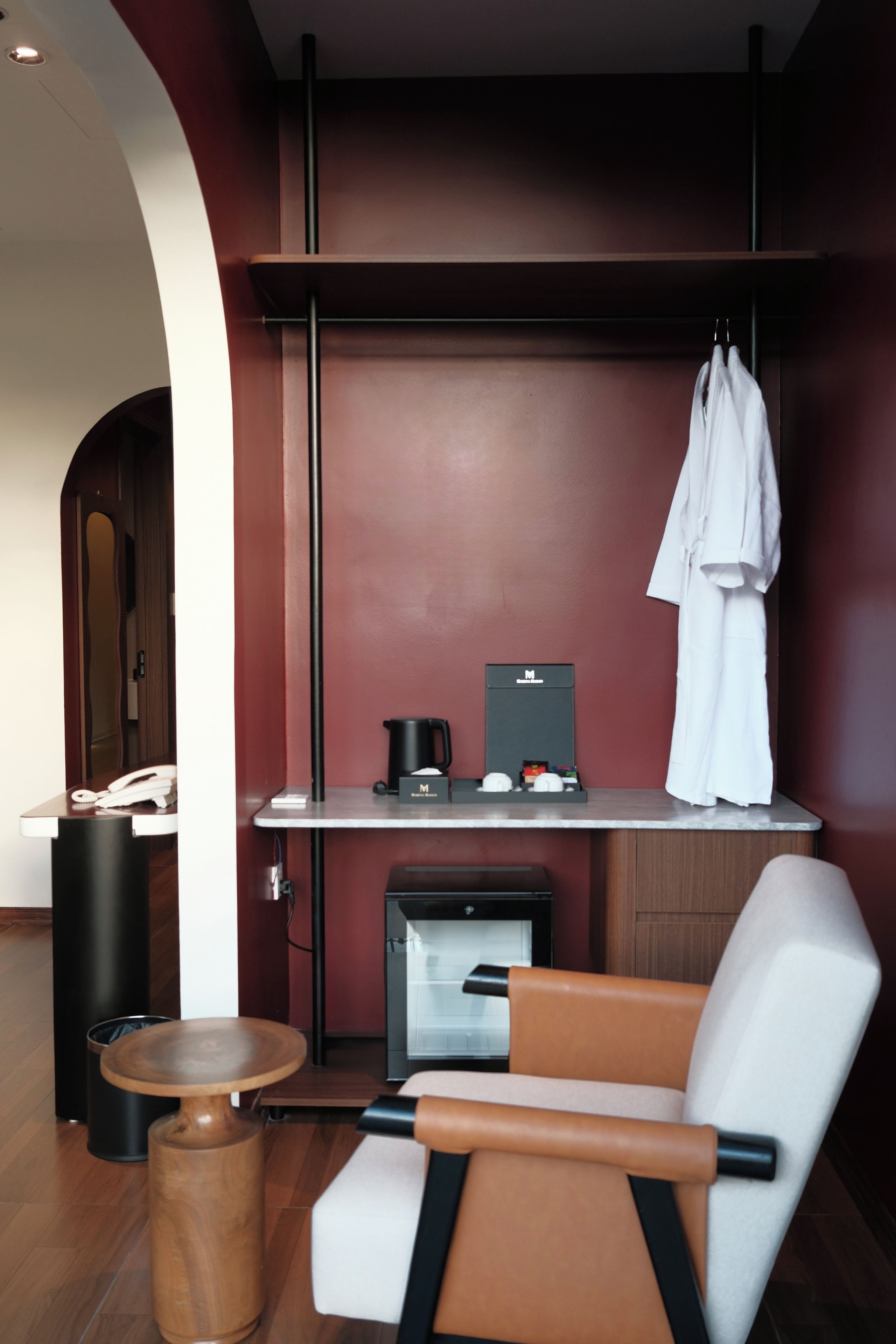 Una habitación de hotel moderna con una zona de estar, una kitchenette pequeña y una bata colgada de un perchero.