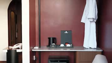 Una habitación de hotel moderna con una zona de estar, una kitchenette pequeña y una bata colgada de un perchero.