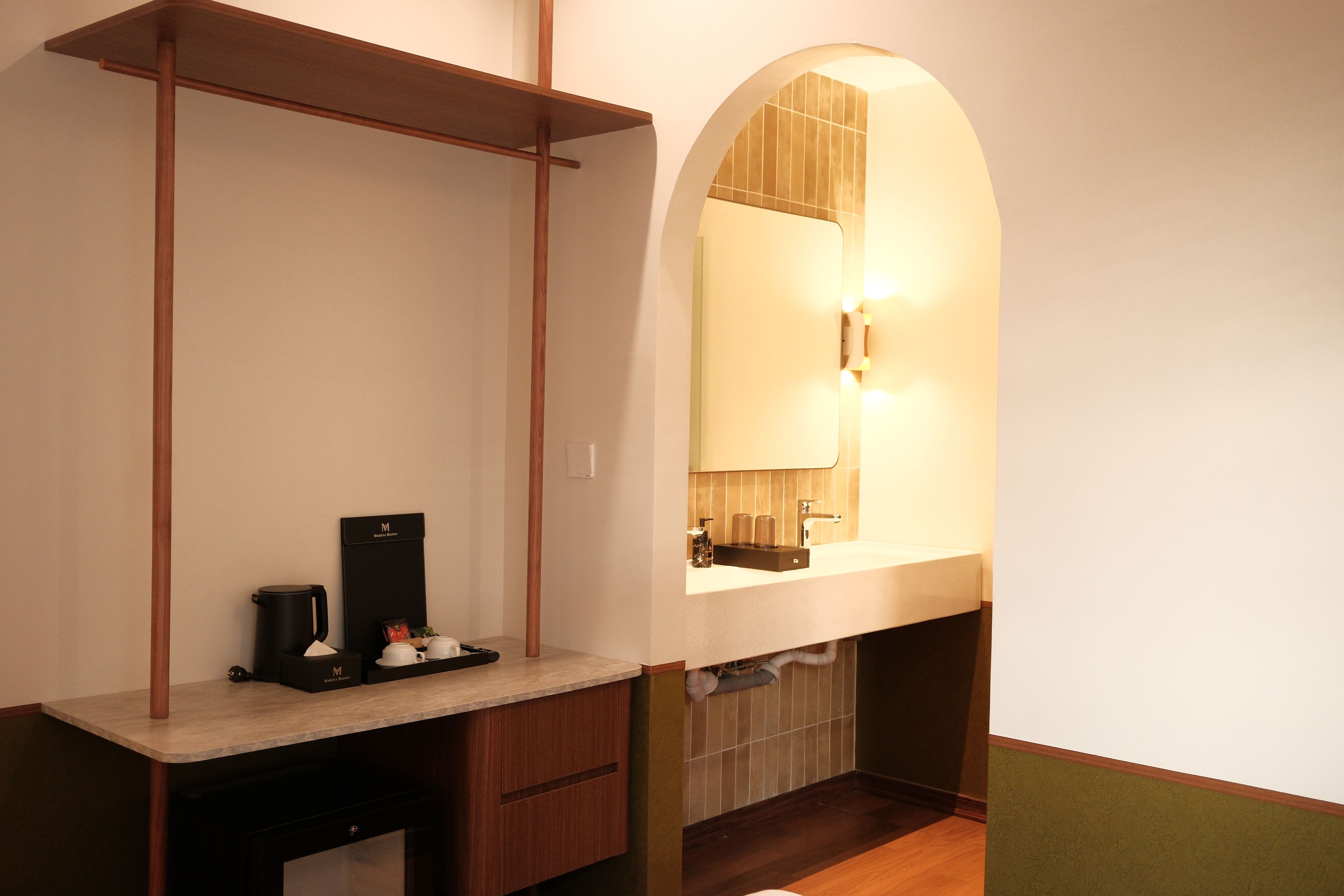 Un baño con tocador de madera, cafetera y espejo con luz.