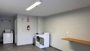 Un lavadero con lavadora, secadora y extintor en la pared.