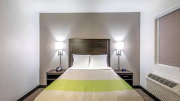Een hotelkamer met een bed, twee nachtkastjes, een wandverwarmer en twee wandlampen.