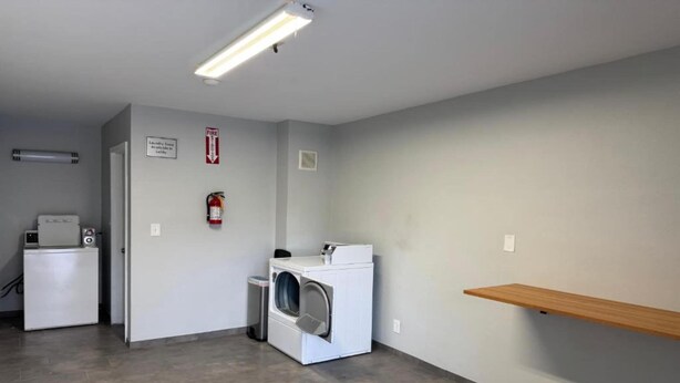 Ein Waschraum mit Waschmaschine, Trockner und einem Feuerlöscher an der Wand.