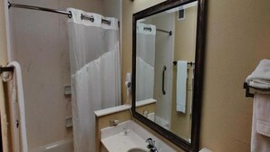 Une salle de bain équipée d’une douche, d’un lavabo, d’un miroir et d’un porte-serviettes.