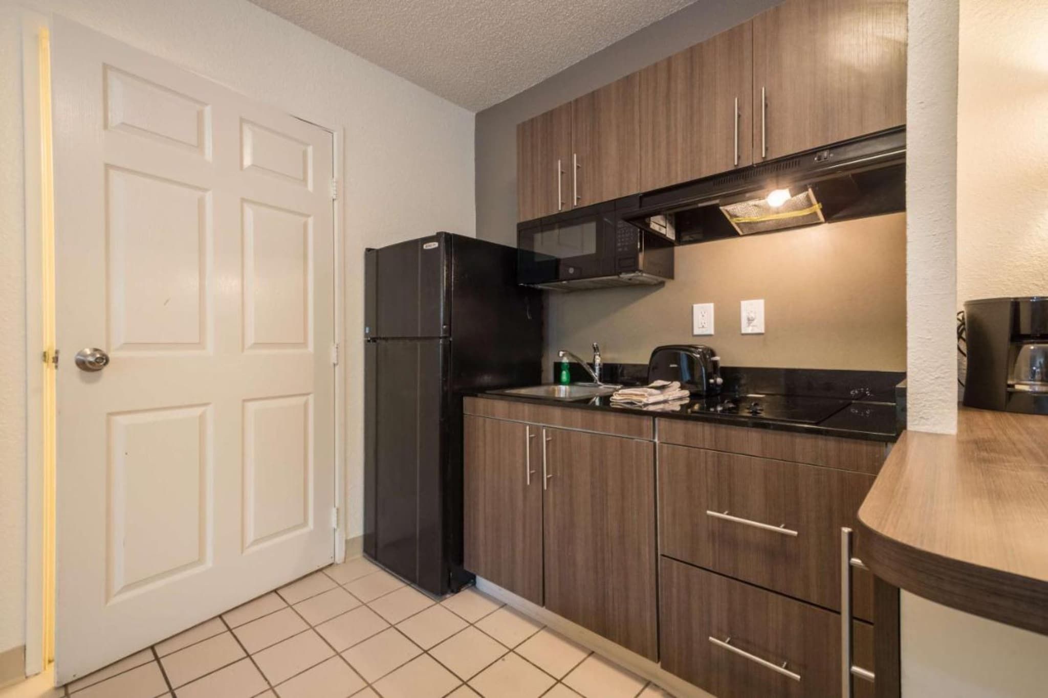 A compact kitchen with a refrigerator, microwave, and a sink.
