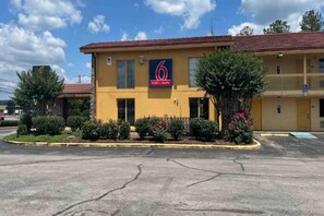 A motel with a yellow facade, a red roof, and a sign indicating it is a 6 motel and studio. - 1 King Bed | Smoking, Kitchen (Huntsville AL)
