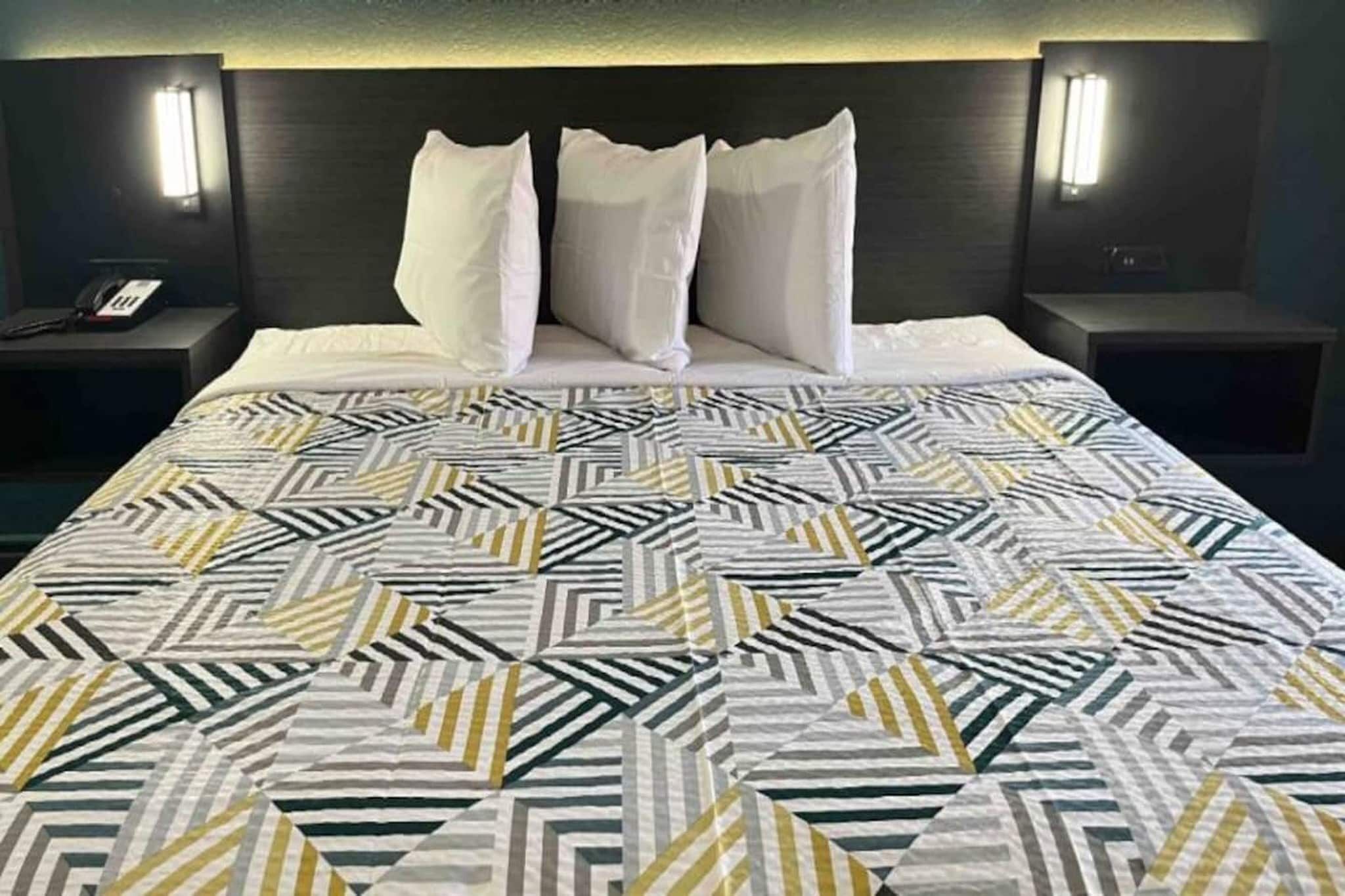 Une chambre d’hôtel avec un lit, deux tables de chevet et une petite table avec un téléphone.