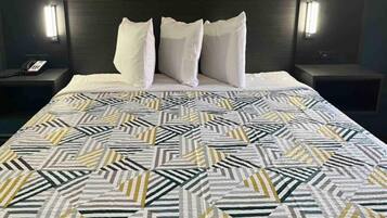 A hotel room with a bed, two bedside tables, and a nightstand with a phone.