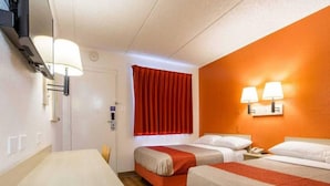 Ein Hotelzimmer mit zwei Betten, einem Schreibtisch, einem Fenster mit roten Vorhängen und Wandlampen.