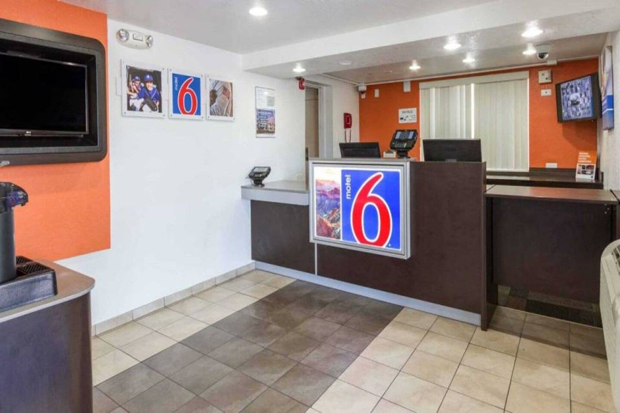 A hotel reception area with a counter, a television, and a sign indicating the hotel name.