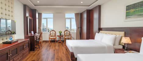 Habitación de hotel con cama, escritorio con silla, televisión y ventana con vista a edificios.