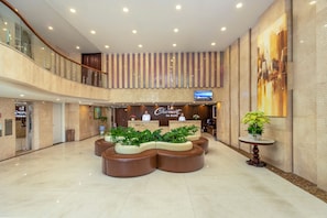 Un hall d’hôtel comprenant un comptoir d’accueil, un espace salon et un grand tableau accroché au mur.