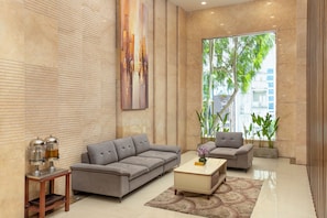 A modern living room with a grey sofa, a coffee table, and a painting on the wall. - Le Charmant Da Nang (An Hai)