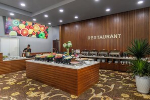 A buffet setup with various food items and a 'RESTAURANT' sign on the wall. - Le Charmant Da Nang (An Hai)