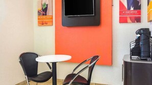 A small room with a television mounted on the wall, two chairs, a small round table, and a coffee machine on a counter. - Spacious 2-bed ADA Room|Free Wifi (Tucker)