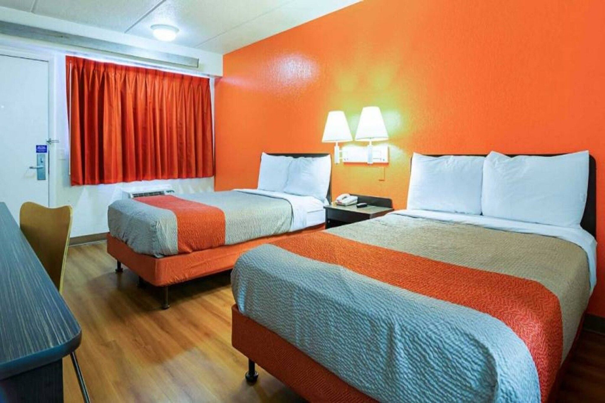 A hotel room with two beds, a desk, and a chair.