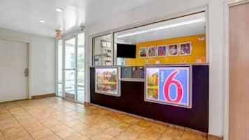 A hotel reception area with a tiled floor, a reception desk, and a large number '6' sign.