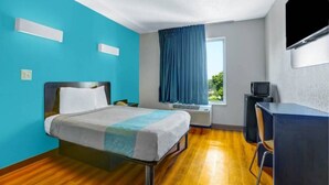 Ein Hotelzimmer mit Bett, Schreibtisch, Fernseher und Klimaanlage.
