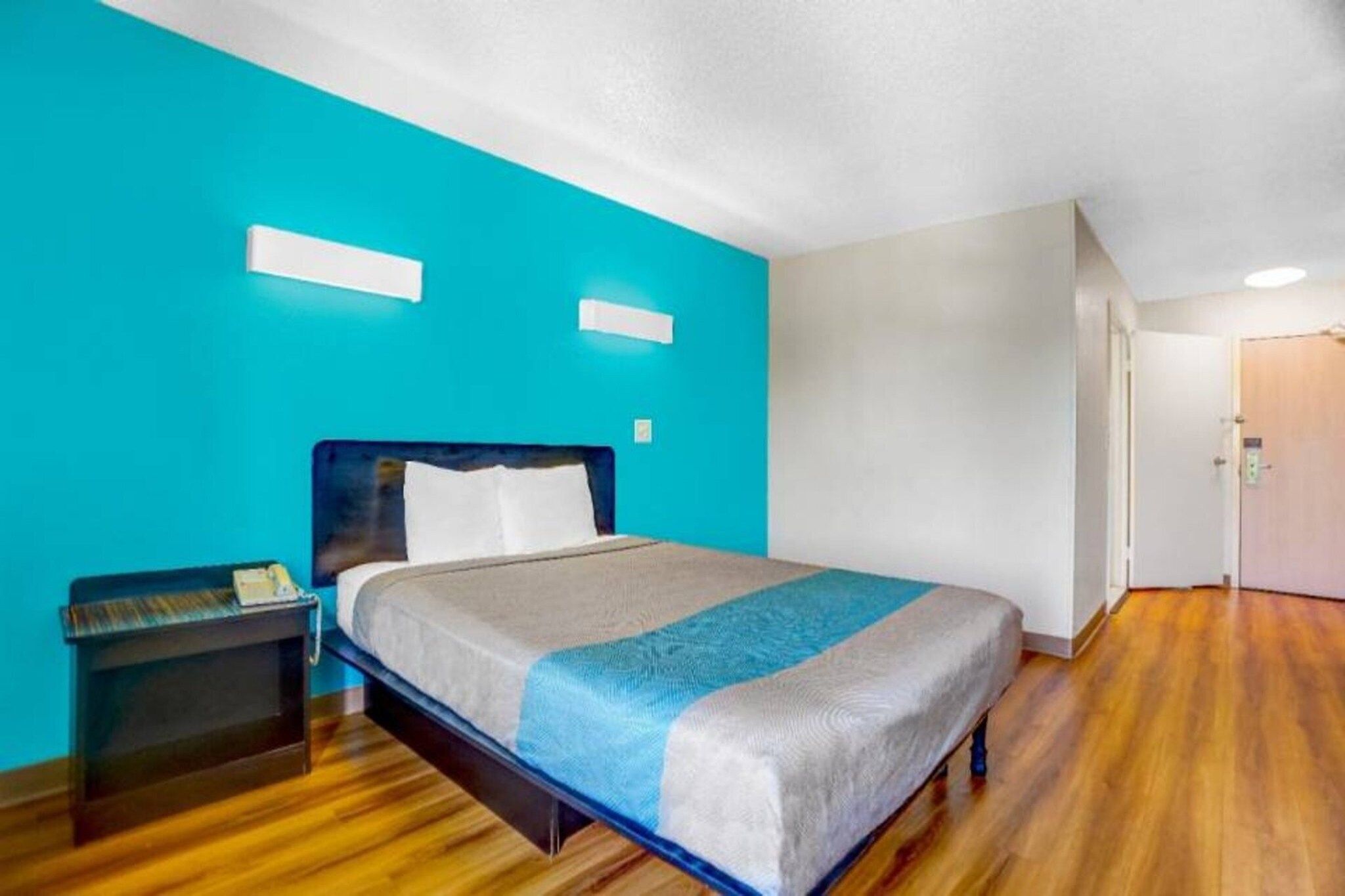 Ein Hotelzimmer mit einem Bett, einem Nachttisch und einer Tür.