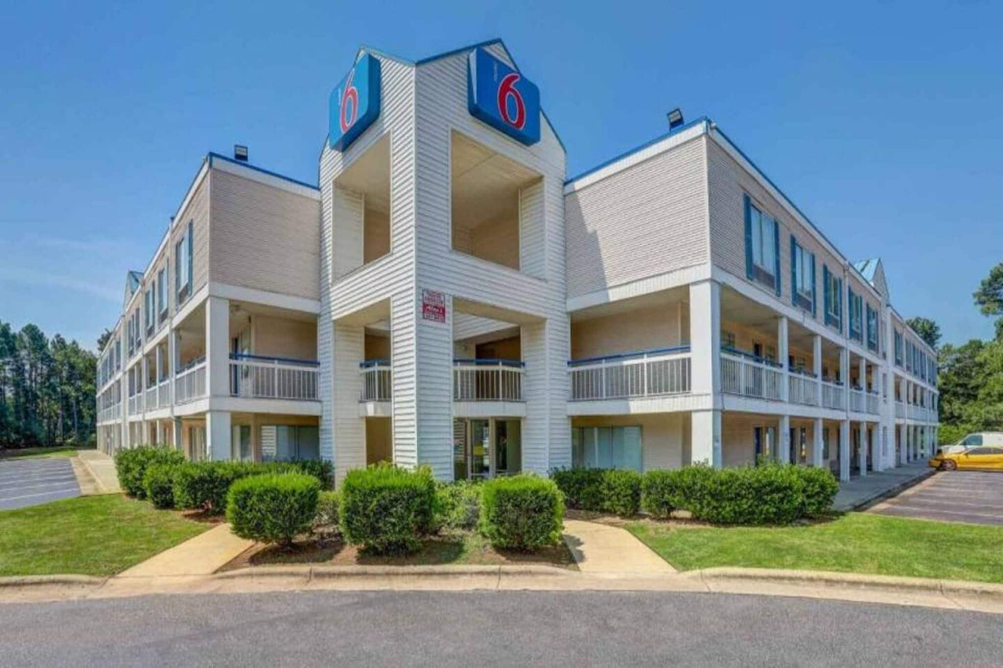 A multi-story motel with a central tower, balconies, and a parking lot.