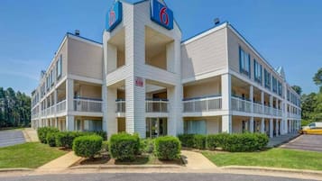A multi-story motel with a central tower, balconies, and a parking lot.
