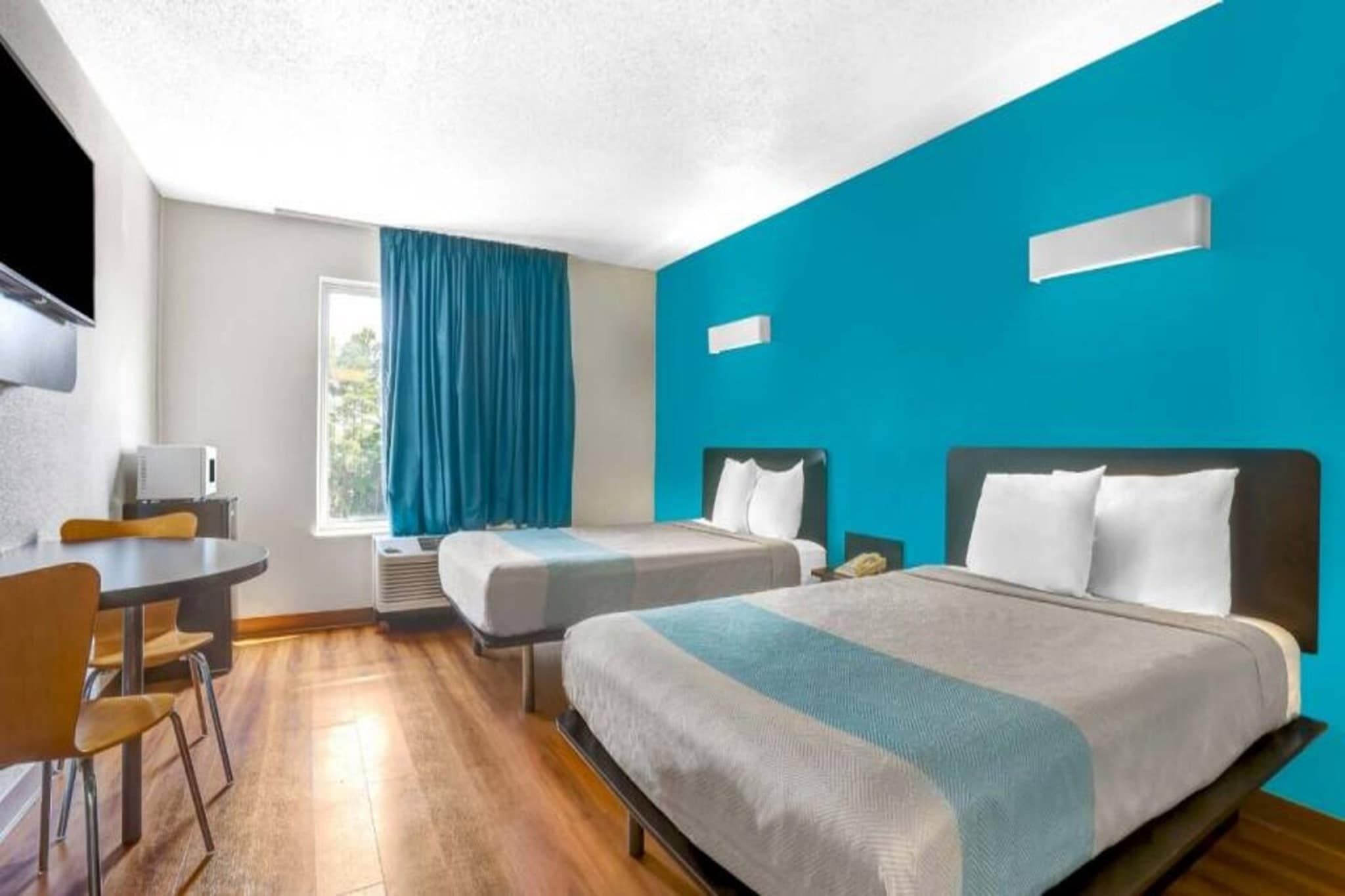 A hotel room with two beds, a desk, and a TV.