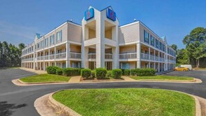 A multi-story hotel with a central atrium, balconies, and a parking lot. - 2 Full Beds | Smoking (Raleigh NC)