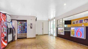 A spacious lobby with a vending machine, a door, and a wall with a number sign. - 2 Full Beds | Smoking (Raleigh NC)