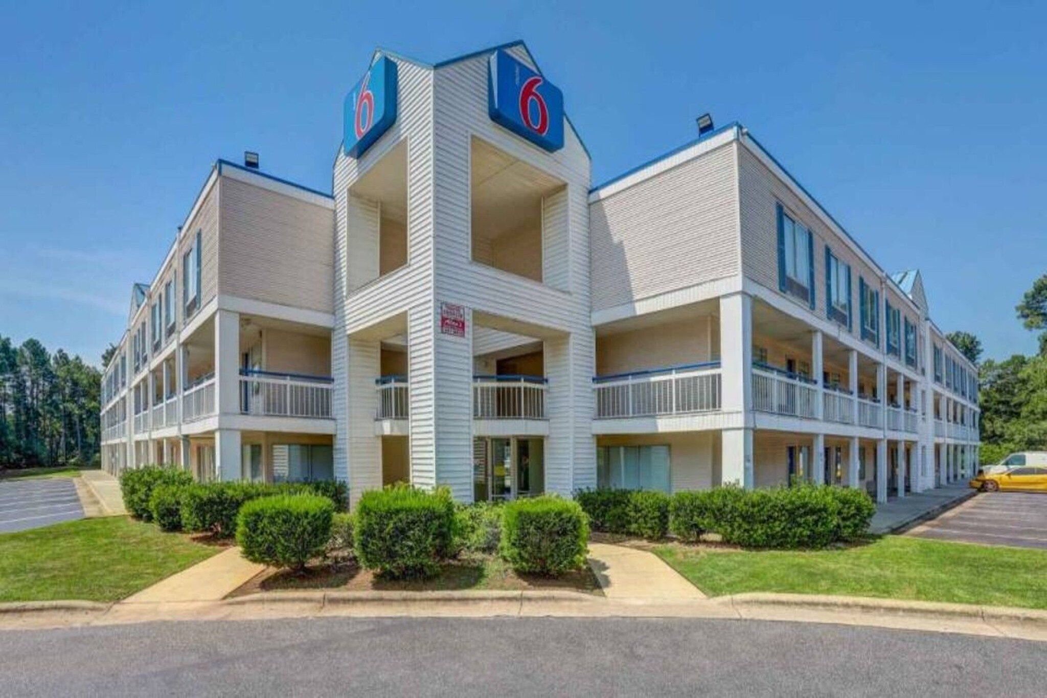 A multi-story motel with a central tower, balconies, and a parking lot.