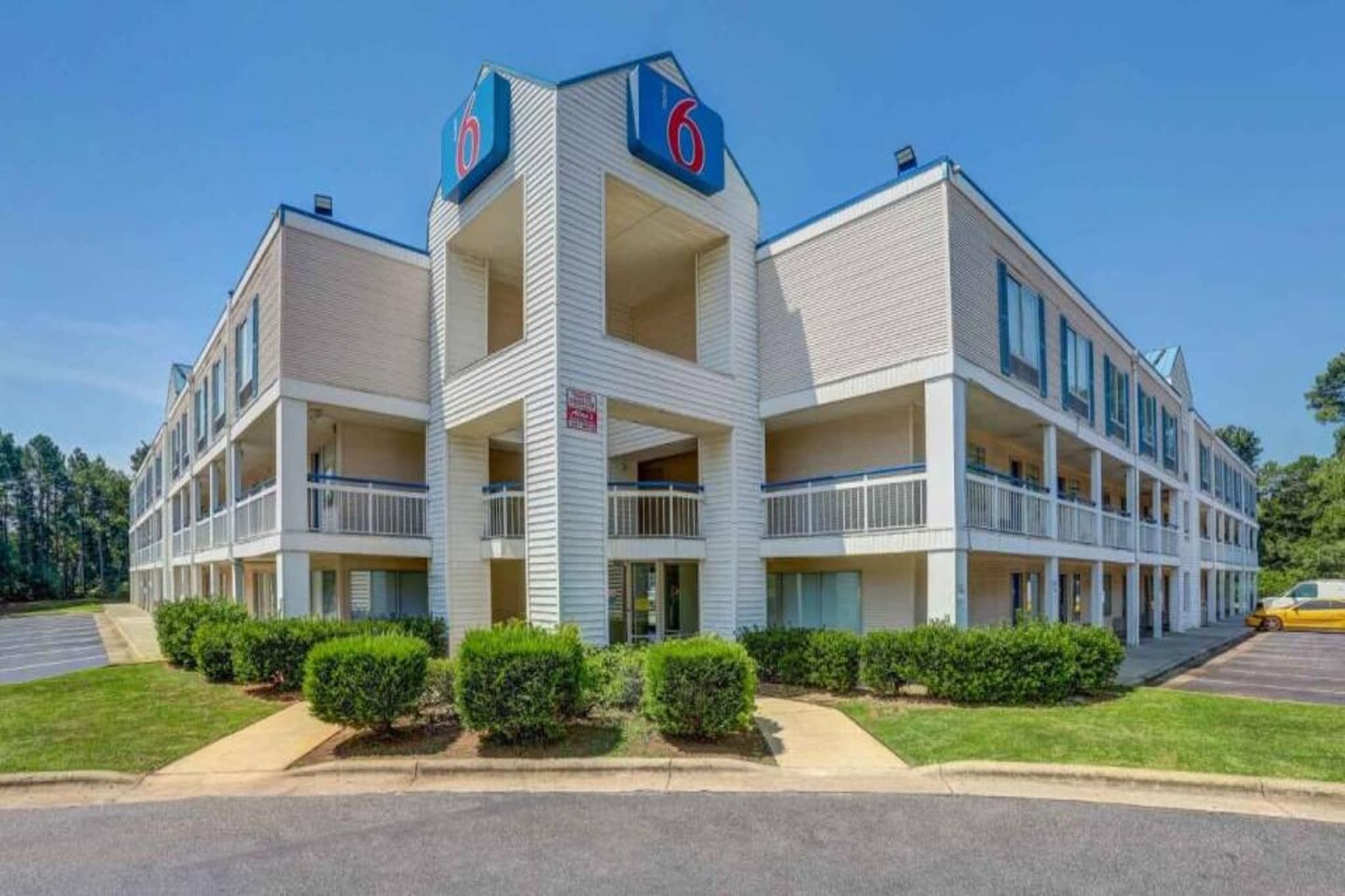 A multi-story motel with a central tower, balconies, and a parking lot.
