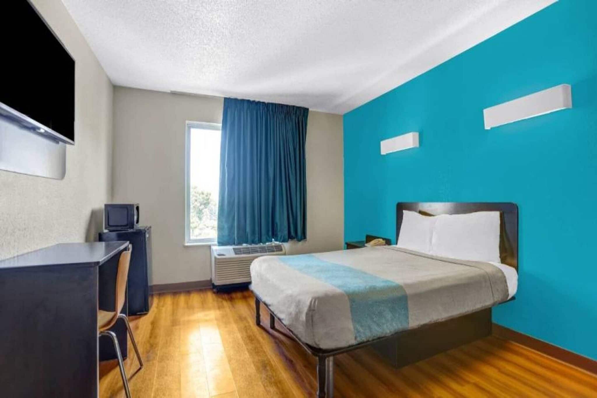 A hotel room with a bed, desk, and a television.