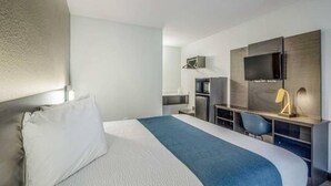 Ein Hotelzimmer mit einem Bett, einem Schreibtisch, einem Sessel, einem Fernseher und einem Kleiderschrank.