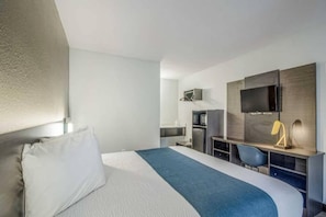 A hotel room with a bed, a desk, a chair, a television, and a wardrobe. - 1 King Bed | Mobil Access Tub Nsmk Kitchen (Groves)