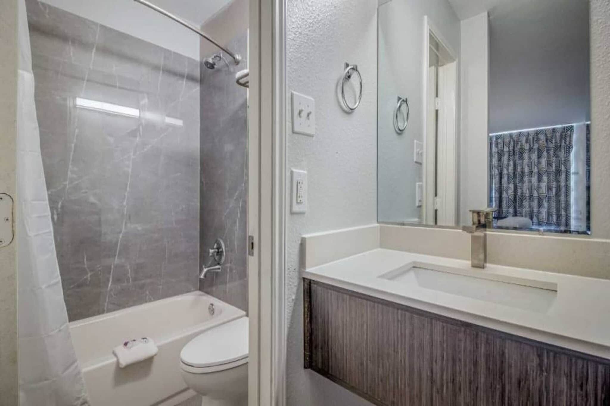 A bathroom with a bathtub, a toilet, a sink, and a mirror.