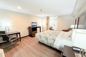 Une chambre d’hôtel équipée d’un lit, d’un bureau, d’une chaise, d’une télévision et d’une petite kitchenette.