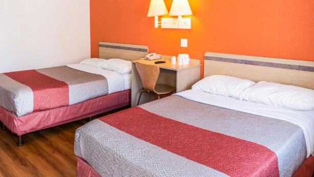 Quarto de hotel com duas camas, uma escrivaninha e uma cadeira.